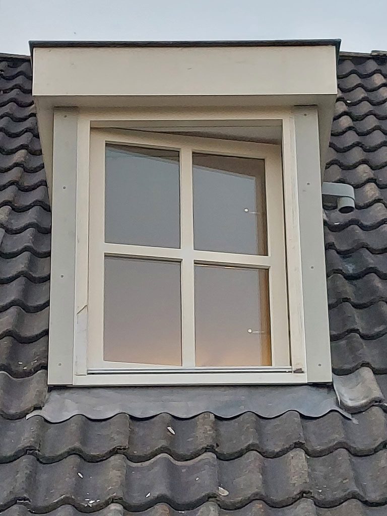 Dakkapel met wit kozijn op een donker pannendak