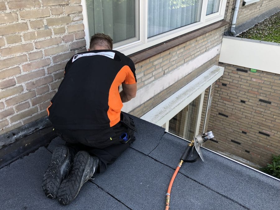 Dakdekker van FB werkt aan de aansluiting van een plat dak op de gevel