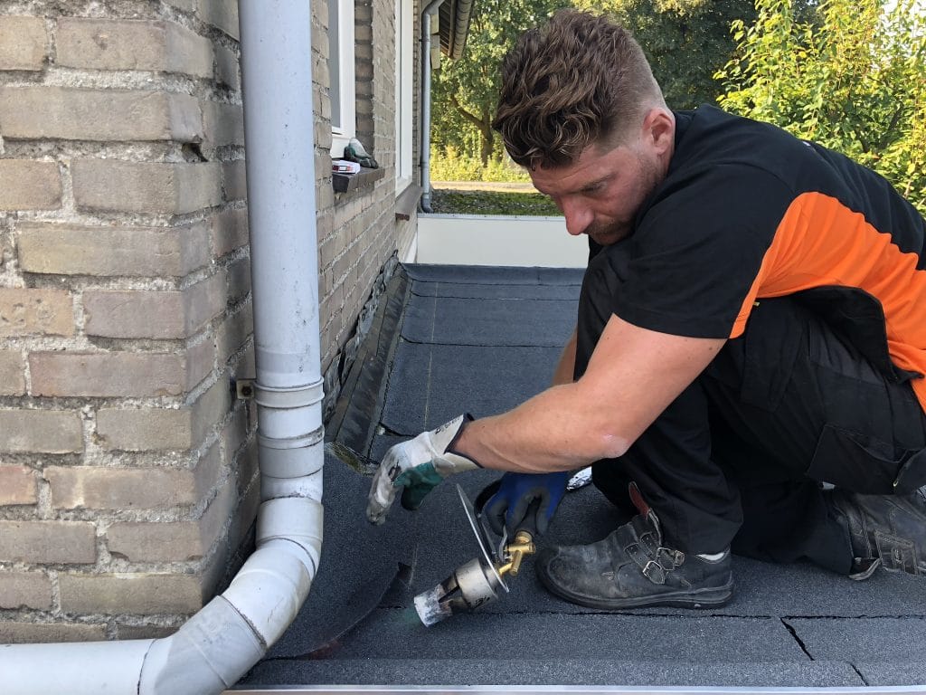 Dakdekker van FB aan het werk met een brander op een plat dak