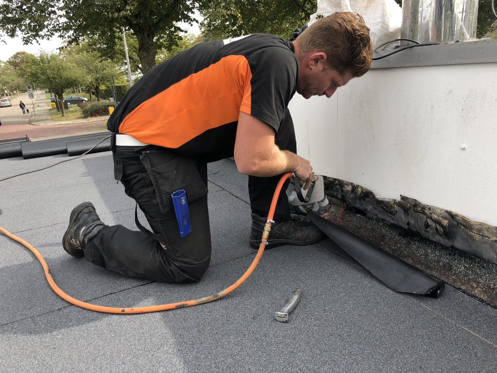Dakdekker van FB werkt de opstand van een plat dak af