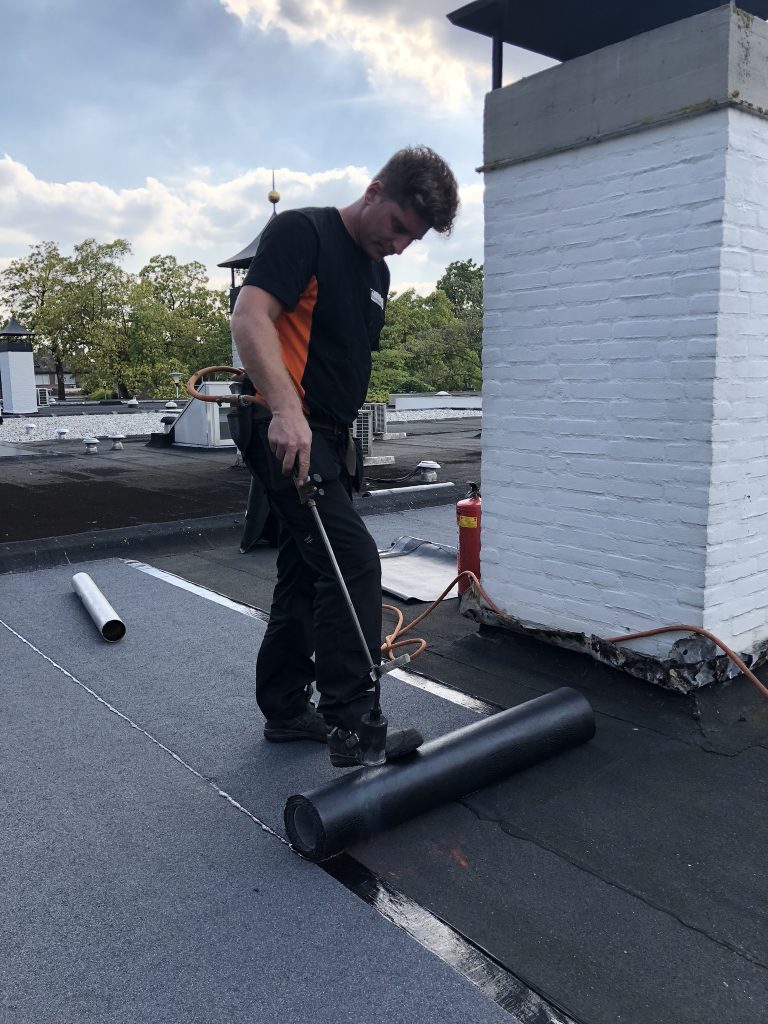 Dakdekker van FB werkt met de brander rond een schoorsteen